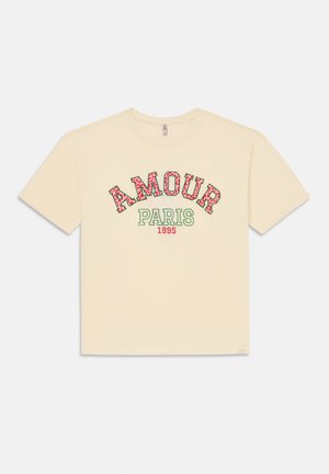 T-shirt crème à manches courtes avec "AMOUR" en lettres rouges à motifs, "PARIS" en vert et "1995" en rouge imprimé sur le devant.