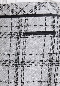 Tissu texturé gris et noir avec un motif tartan classique, comportant des fils métalliques subtils et une bande d'accent noire lisse.
