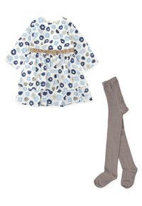 Vestido floral en blanco, azul y gris con mangas largas, una falda de capas y una cinturilla beige; combinado con medias grisáceas.