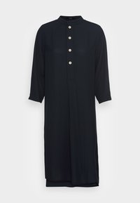 Abito nero a maniche lunghe con colletto rialzato e cinque bottoni bianchi sul davanti. Tessuto morbido, taglio dritto, lunghezza al ginocchio, design minimalista.