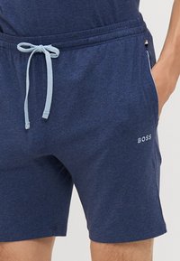Marinblå shorts i stretchmaterial, med resårmidja och dragsko, sidofickor och en liten vit "BOSS"-logotyp på vänstra låret.