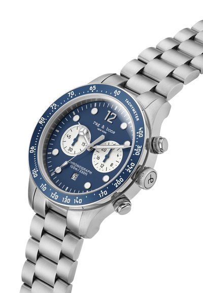 Meeste roostevabast terasest kronograafkell, millel on sinine kellanägu, hõbedased aktsendid, takümeeter ja link-käevõru. Omab kahte alalugemist ja kuupäevaaken.