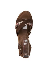 Brown suede sandal with crisscross floral fabric straps, clear plastic heel, and an adjustable ankle buckle. Flat sole with stitching details.