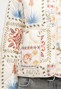 Μπουφάν με καπιτονέ υφή και πατς με εκτυπώσεις θαλασσινού θέματος, όπως καβούρια, κοχύλια, αστερίες, φυτά αγάβης και κείμενο όπως "VACANCES" και "AGAVE".