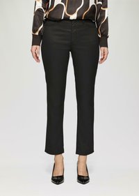 Schwarze Hose mit schlankem Schnitt, aus glattem Stoff. Mit einer mittelhohen Taille und dezentem Fronttaschenstich versehen. Getragen mit schwarzen Absatzschuhen.