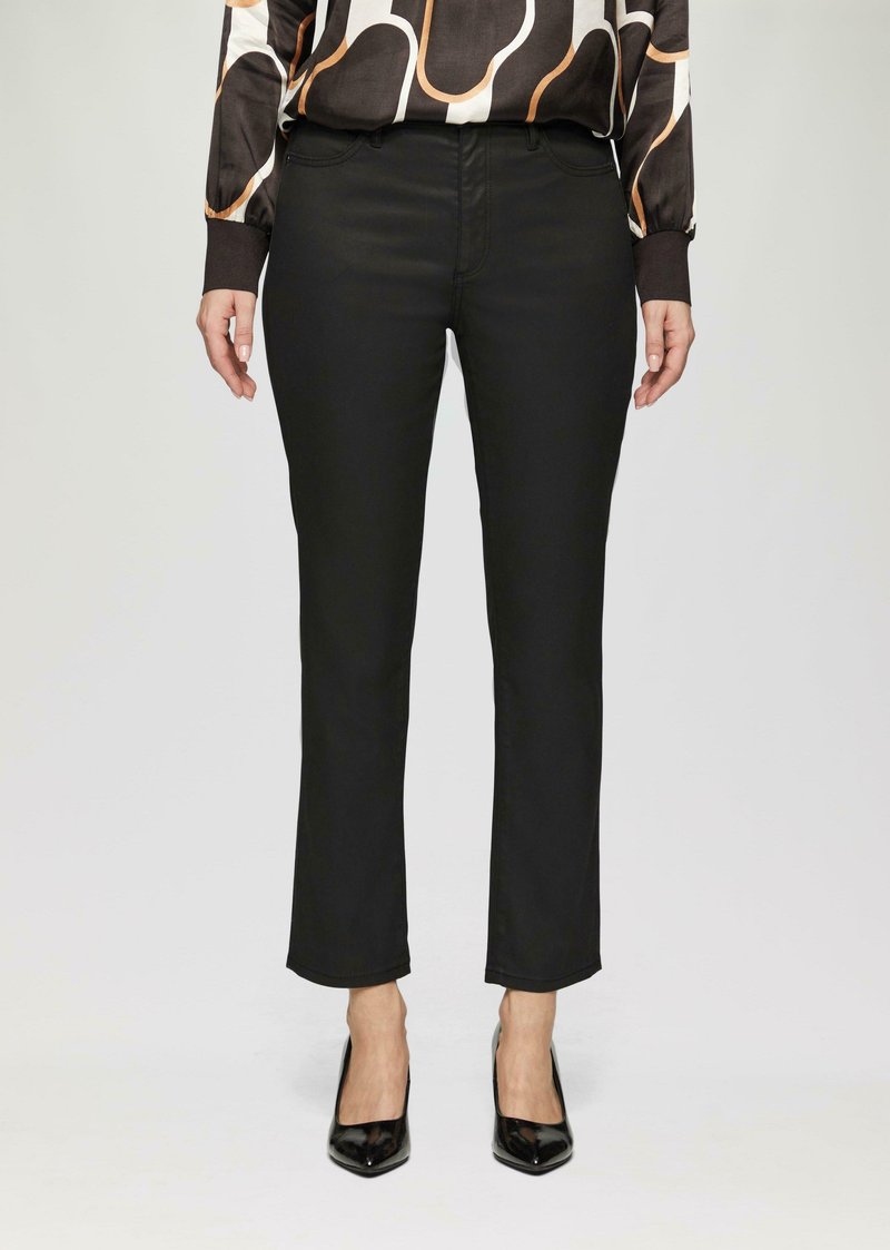Schwarze Hose mit schlankem Schnitt, aus glattem Stoff. Mit einer mittelhohen Taille und dezentem Fronttaschenstich versehen. Getragen mit schwarzen Absatzschuhen.