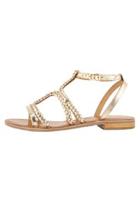 Sandalini piatti metallici oro con accenti intrecciati, design aperto, cinturino alla caviglia regolabile e soletta in pelle marrone. Tacco basso.
