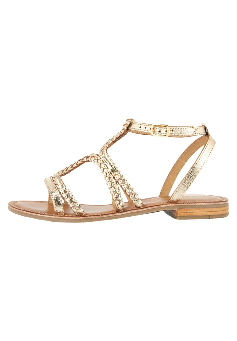 Sandalini piatti metallici oro con accenti intrecciati, design aperto, cinturino alla caviglia regolabile e soletta in pelle marrone. Tacco basso.