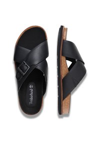 Sandales en cuir noir avec un design à lanières croisées, semelle intermédiaire en liège, semelle intérieure texturée et semelle extérieure en caoutchouc. Logo Timberland sur la semelle intérieure.