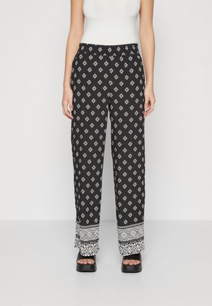 Pantalones negros estampados con diseños de diamantes blancos, de pierna ancha, cinturilla elástica y un dobladillo texturizado con acentos geométricos en la parte inferior.