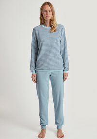 Lichtblauwe, lange mouwen gestreepte top met een ronde halslijn; bijpassende effen lichtblauwe broek met omslagen aan de enkels. Zachte stofstructuur.