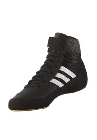 Svart hög tops sportskor med ett texturerat tygövre, snörning och tre vita ränder på sidan. Gummisula med lätt krökning.