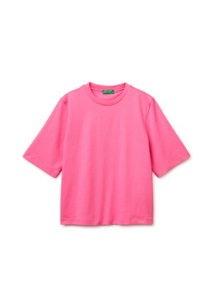 Jasnoróżowy bawełniany t-shirt z krótkim rękawem, dekoltem typu crew i zieloną metką marki wewnątrz kołnierza.