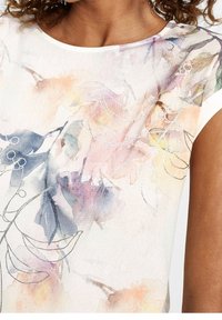 Kortärmad topp i ett mjukt, strukturerat tyg med ett akvarellblommigt mönster i pastellfärgerna rosa, blått och orange, accentuerat med silverstickning.