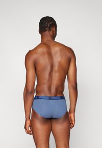 Männerunterwäsche in Blau mit elastischem, schwarzem Bund, der das "PUMA"-Logo trägt. Aus Baumwolle, enganliegend und mit glatter Textur.