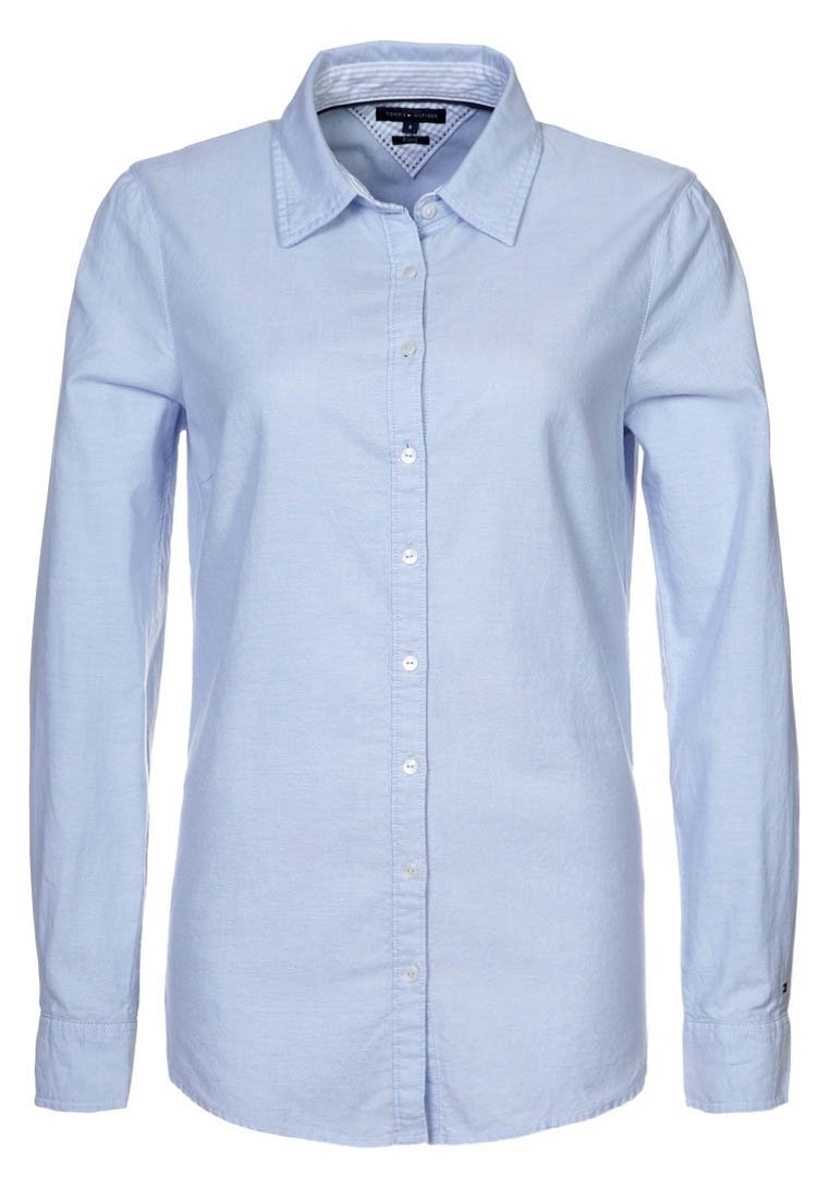 Ljusblå långärmad skjorta med knappar som har klassisk krage, frontknäppning och en slät, vävd textur.