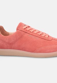 Pink suede sneaker with tonal laces, smooth interior, and light rubber sole featuring a textured grip. Minimalist design with no visible logos.