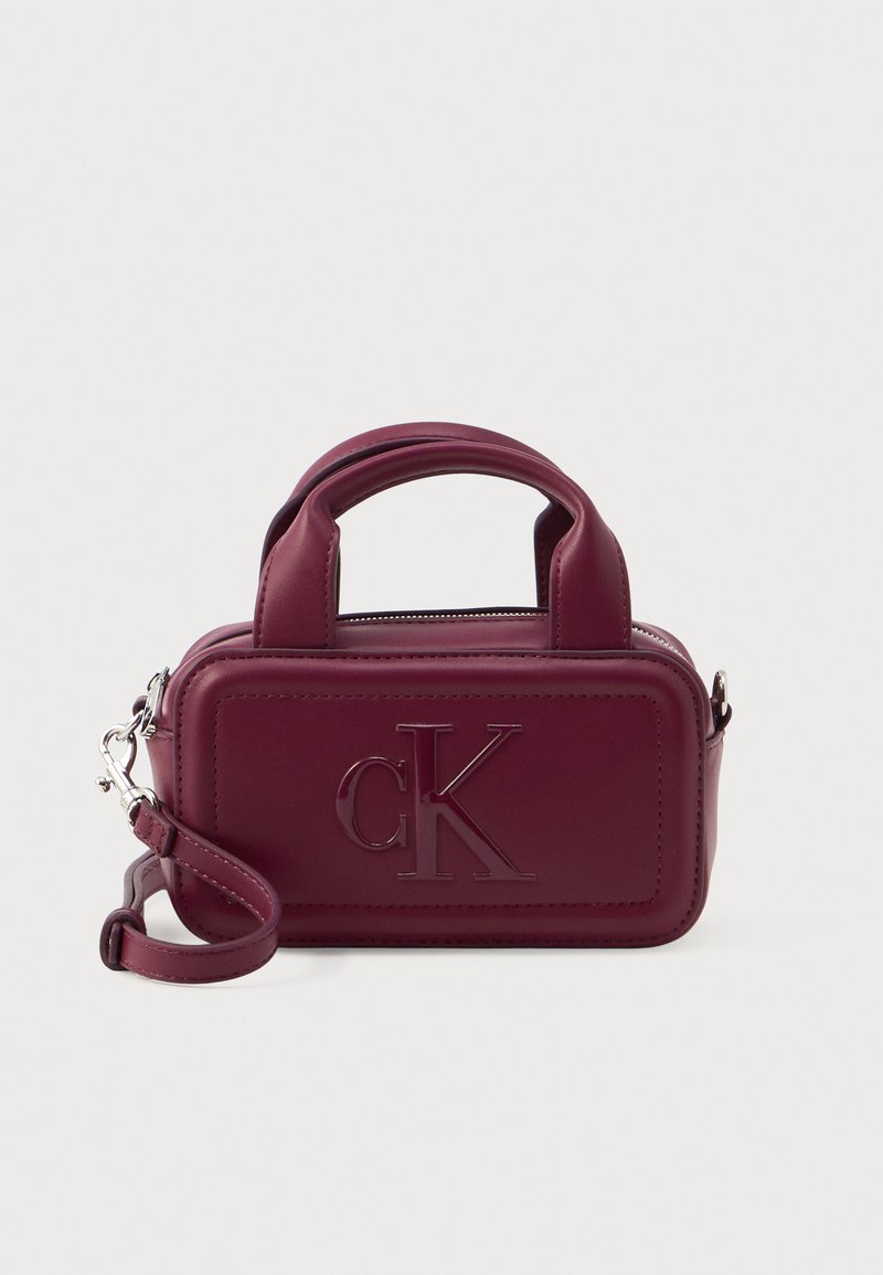 Bordo zipsovaný kabelka z hladkého syntetického materiálu, s dvojitými krátkymi ušami, odnímateľným ramenným popruhom a embosovaným logom "CK".
