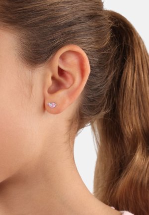 Pendientes de plata con un diseño de caracol esmaltado en rosa, con una superficie suave y un brillo sutil, llevados en la oreja de una persona.