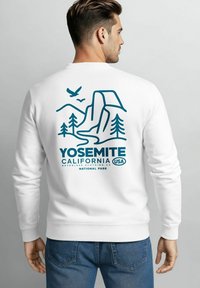 Weißer Pullover mit einem türkisfarbenen Grafikdesign von Yosemite, das Berge, Bäume und den Text "Yosemite California USA" zeigt.