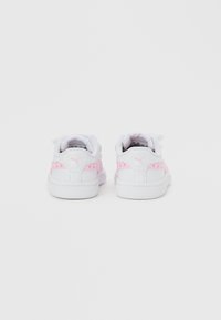 Λευκά αθλητικά παπούτσια για νήπια με ροζ ριγέ διακοσμημένη με σχέδιο καρδιάς και λογότυπο Puma στη φτέρνα, ορατά από πίσω σε λευκό φόντο.