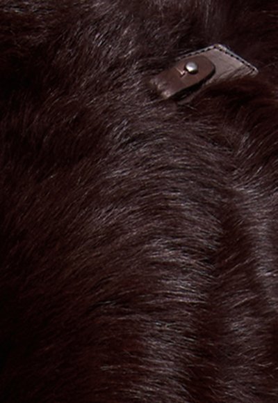 Texture di pelo marrone scuro con una piccola striscia di pelle e un dettaglio con bottone in argento parzialmente visibile sul lato superiore destro.
