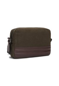Olivengrønn tøy crossbody-veske med en brun lærbunn, glidelås og justerbar stropp. Strømlinjeformet rektangulært design.