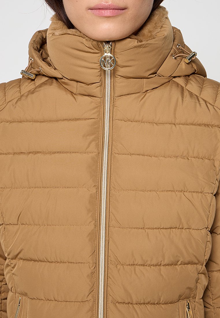 Beige Pufferjacke mit hohem Kragen und Reißverschlussfront. Verfügt über einen Logo-Reißverschlussanhänger und genähte horizontale Paneele für Textur.