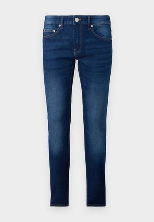 Sötétkék, slim fit farmernadrág, denim anyagból. Öt zsebbel, gombos záródással és enyhe elhalványulással a lábak mentén.