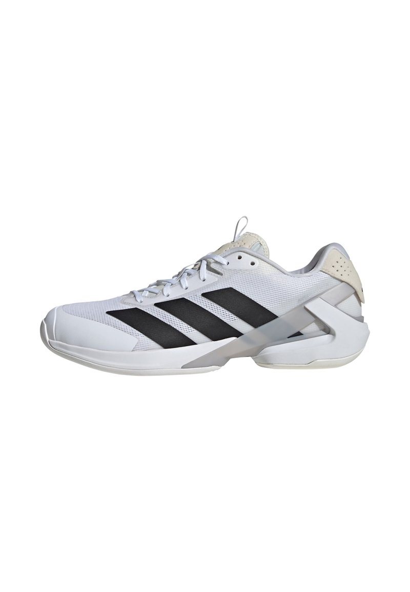 Zapatilla deportiva blanca con rayas negras, parte superior de malla, cuello acolchado y talón reforzado. Suela de goma diseñada para agarre y soporte.