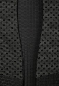 Textile noir avec des textures contrastées ; un côté présente un motif hexagonal, tandis que l'autre a un design en maille avec des perforations circulaires.