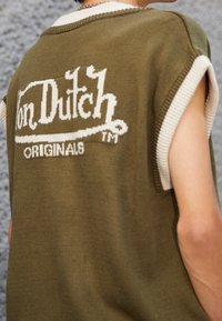 Hedvábný olivově zelený top bez rukávů s bílým žebrovaným výstřihem a švy na ramenech, se znakem "Von Dutch Originals" v bílé barvě.