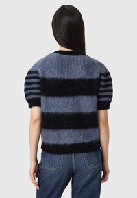 Kurzarmpullover aus Strick mit horizontalen schwarz- grauen Streifen, flauschiger Textur und Rundhalsausschnitt. Kombiniert mit hochsitztenden Jeans.