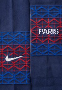 Nike ponožky s námorníckym pozadím, červenými a modrými geometrickými vzormi a textom "PARÍŽ" v bielej farbe, s bielym „swoosh“ logom na jednej strane.