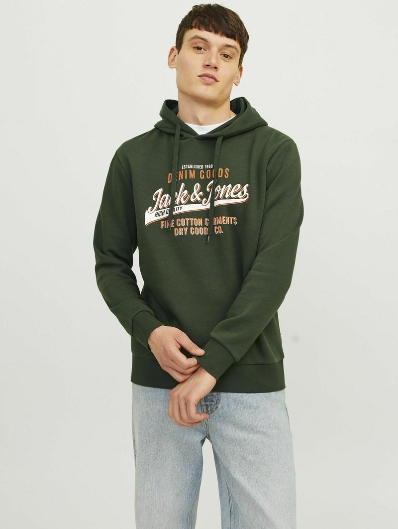 Sudadera verde de algodón con un bolsillo canguro, capucha con cordones y texto gráfico en el frente. Combinada con jeans de color azul claro. Textura suave.