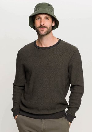 Pullover in maglia di un verde scuro e testurizzato, con un colletto a girocollo e polsini a coste, abbinato a un cappello a secchiello verde coordinato.