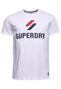 Bílý bavlněný tričko s velkým logem "SUPERDRY" v tmavě modré barvě, s červenými a modrými pruhy nad ním. Krátké rukávy, kulatý výstřih.
