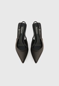 Μαύρες γόβες slingback με αιχμηρή μύτη, ματ σατέν υφή και λουράκι με ασημένια πόρπη. Ο λογότυπος της φίρμας είναι ορατός στο εσωτερικό.