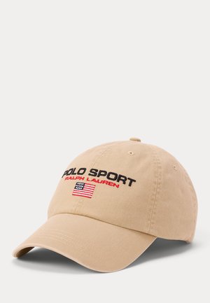 Gorra de béisbol beige con texto "Polo Sport Ralph Lauren" y una pequeña bandera americana bordada en el panel frontal.