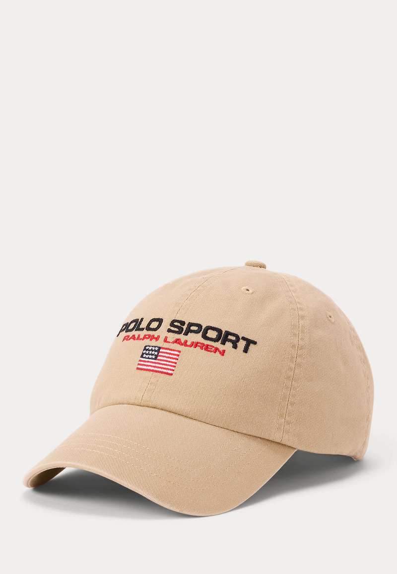 Μπεζ καπέλο μπέιζμπολ με κείμενο "Polo Sport Ralph Lauren" και μια μικρή κεντημένη αμερικανική σημαία στο μπροστινό πάνελ.