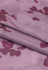 Tessuto viola con una texture liscia, caratterizzato da un motivo di forme floreali bordeaux scuro e design astratti. Piegato con morbide pieghe.