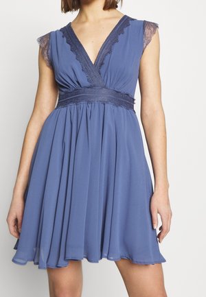 Robe bleue sans manches avec bordure en dentelle aux épaules et à l'encolure, taille cintrée, et jupe plissée fluide se terminant au-dessus des genoux.