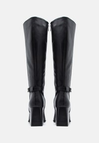 Stivali neri al ginocchio realizzati in pelle con una texture liscia, dotati di chiusura con zip e di un tacco spesso con un motivo a scanalature orizzontali.