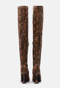 Overknee-Stiefel aus braunem und schwarzem Schlangenleder mit strukturierten Oberflächen und einzigartigem spitzem Absatzdesign. Reißverschlussdetails an den Seiten.