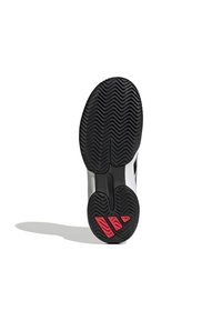 Shoe sole with a black rubber surface, featuring a zigzag pattern and red accents. Slim design with grooves for traction and stability.
