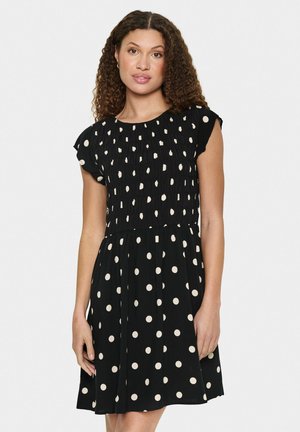 Black short-sleeve dress with white polka dots, featuring a pleated bodice and a flared skirt, made of lightweight fabric.