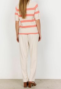 Striped short-sleeve sweater in cream with pink horizontal stripes, paired with light beige, loose-fit trousers and brown block-heeled sandals.