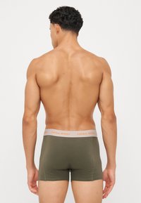 Olivgrüne Boxershorts mit einem grauen Bund und orangefarbener Schrift. Glattes Material, figurschnitt und mittellange Beine.