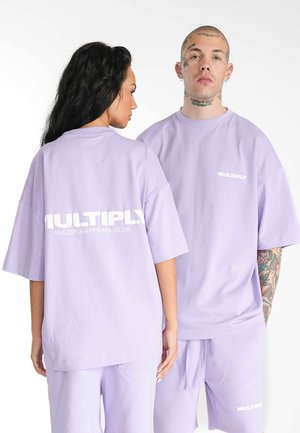 T-shirt oversize di cotone lilla con logo "MULTIPLY" sulla schiena e sul petto, maniche morbide e texture liscia. Stile casual.