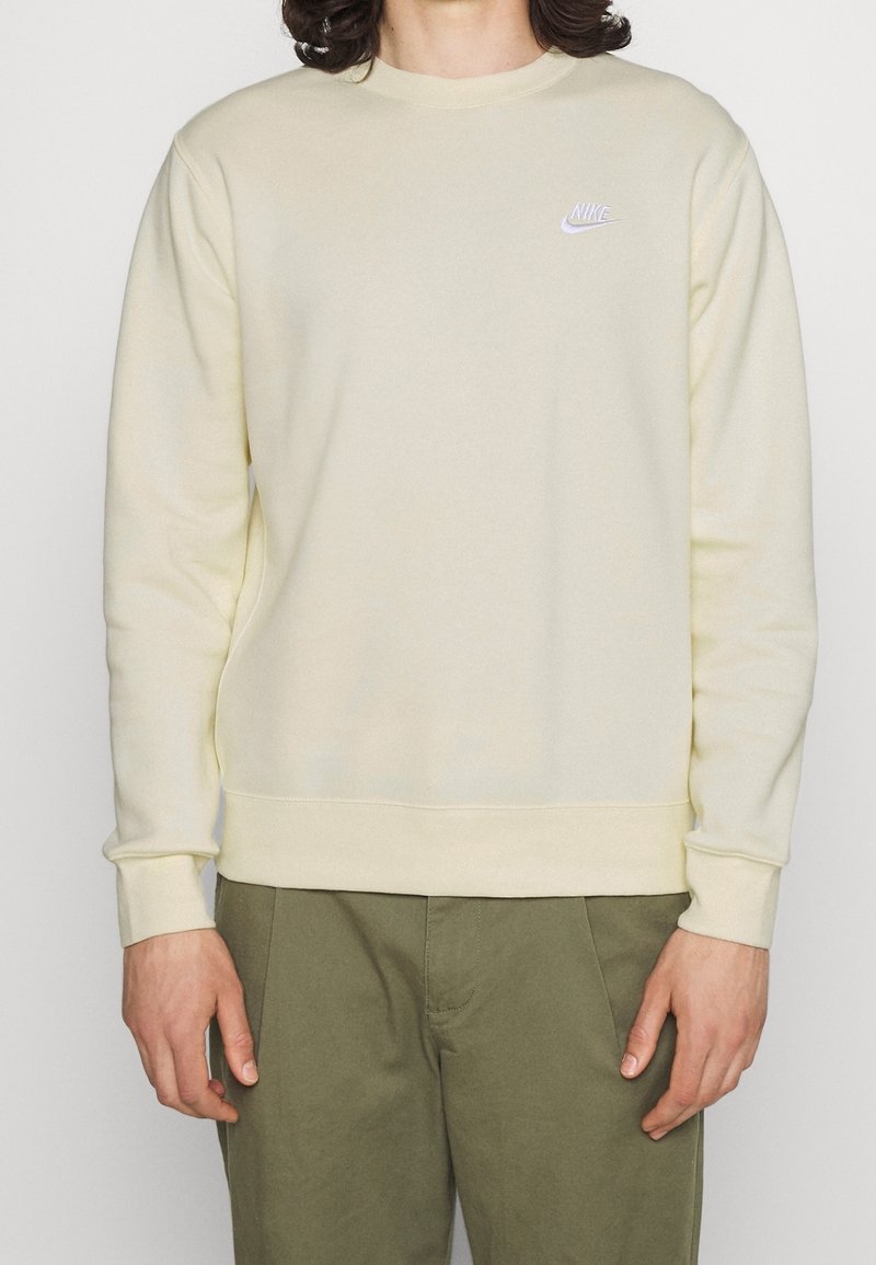 Sudadera de un amarillo claro, fabricada con una tela suave, que presenta un cuello redondo, mangas largas y un pequeño logo de Nike blanco en el pecho.